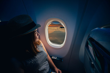 Young asian woman traveler looking view at window in airplane with happiness and relaxing