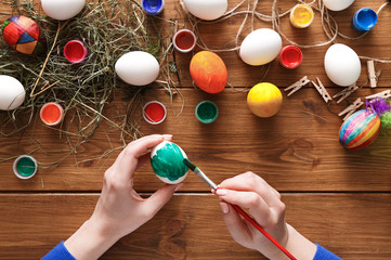 Painting colorful easter eggs, top view on wood