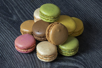 Macarons de couleurs différentes en tas sur fond noir