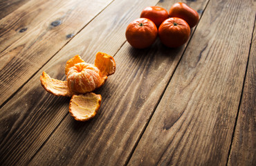 ripe mandarins and peeled mandarin on a wooden bacground