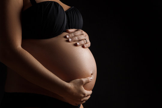 Femme enceinte avec les mains sur le ventre en studio