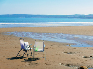 Fototapeta na wymiar Chairs on deserted beach
