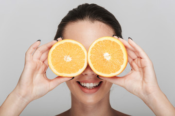 young woman covering eyeswith halves of orange isolated on white