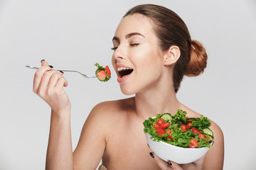 young woman eating healthy salad isolated on white