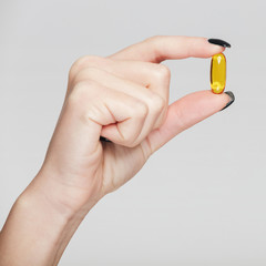 cropped shot of woman holding fish oil capsule isolated on white