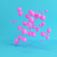 Pink flying spheres on bright blue background in pastel colors