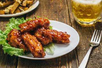 Chicken wings with lettuce, rusks and beer on a wooden table