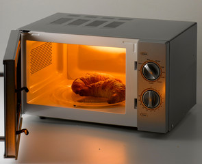 croissants on a plate into an open microwave oven