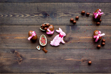 Easter composition. Easter sweet gift. Chocolate eggs near cookies in shape of Easter bunny on dark wooden background top view space for text