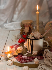 Mug of hot chocolate drink with marshmallow candies on top and candles on white background. Valentin's day love concept.