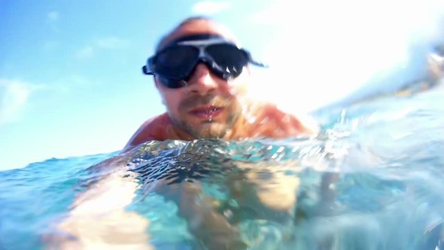 Portrait of a young man with glasses taking himself off to the camera under water.
