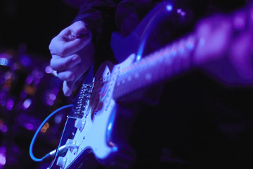artist Guitarist hand play electricity guitar on concert stage with blue light, Practicing in...