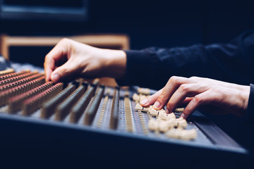 male sound engineer hands working on audio mixing console. music background