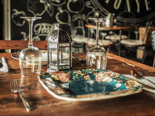 romantic plate setting in a cute vintage cafe on a wooden table with wine glasses