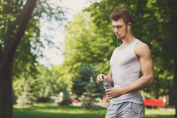 Fitness man in earphones with water otdoors
