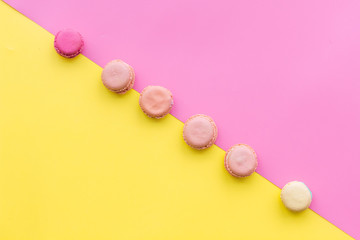 Macarons dessert. Pattern on yellow and pink pastel background top view copy space