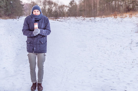 young man holds thermos in the woods in winter. concept
