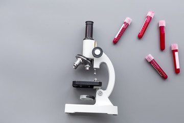 Do blood test in laboratory. Analysis. Blood samples in test tubes near microscope on grey background top view copy space