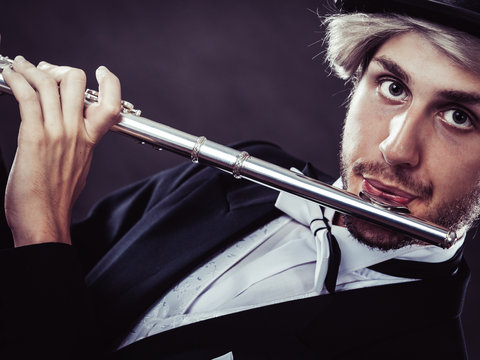 Elegantly dressed male musician playing flute