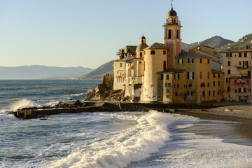 Fototapeta na wymiar waves of rough sea shuttering in front of apse of Assunta church and Dragonara castle, Camogli, Italy