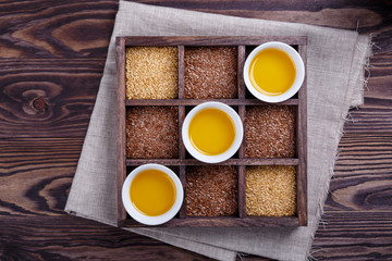 Golden and brown flax seeds and linseed oil on dark wooden background.