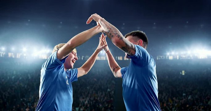 Happy soccer player celebrate a victory on a professional football stadium. He wears unbranded soccer clothes.