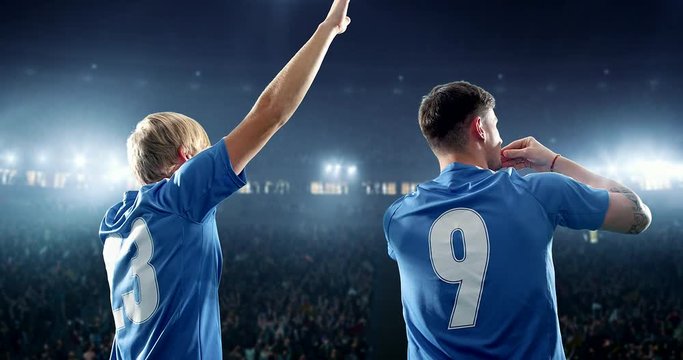Happy soccer player celebrate a victory on a professional football stadium. He wears unbranded soccer clothes.