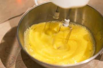 Beat egg with a white mixer in an iron bowl