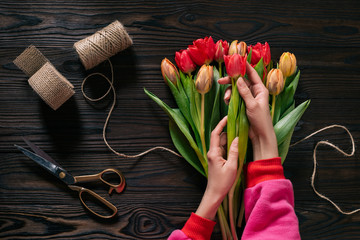Fototapeta na wymiar Partial view of female hands, rope, scissors and bouquet of flowers on wooden surface
