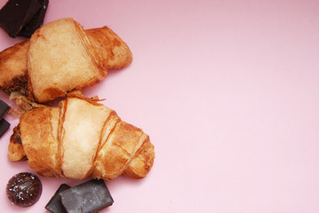 Croissant with Chocolate Pieces with Pink Background with Copy Space for Text.