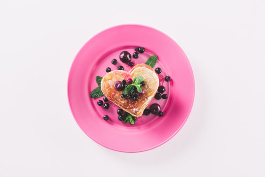 top view of heart shaped pancake with berries and mint isolated on white, valentines day concept