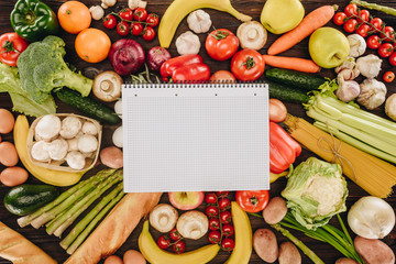 top view of empty notebook on vegetables and fruits on wooden table, grocery concept