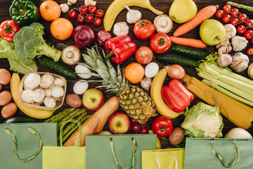 top view of vegetables and fruits with paper bags on wooden table