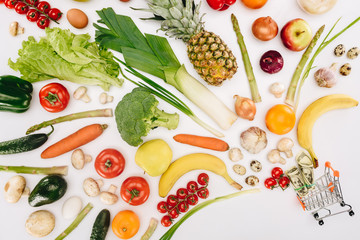 top view of small shopping cart with dollars and fruits with vegetables isolated on white