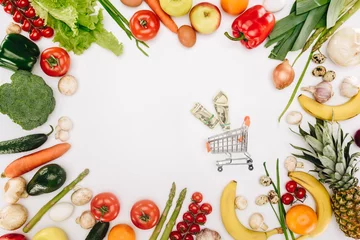 Gordijnen top view of small shopping cart with dollars between vegetables and fruits isolated on white © LIGHTFIELD STUDIOS