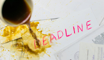 Pouring coffee on the inscription deadline against the background of scattered papers.
