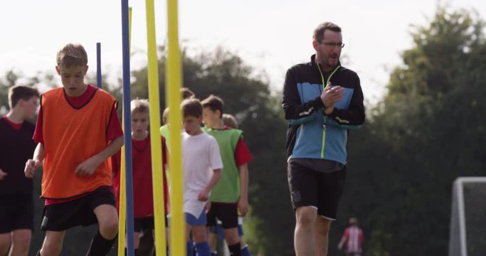 A Soccer coach is pleased with a young player and gives him a high five during training session.Shot on RED Epic
