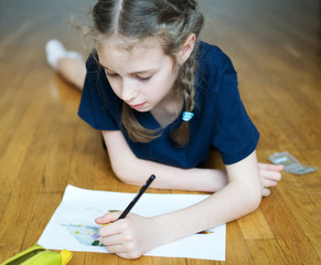 Little girl drawing with pencil at home.