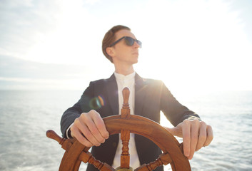 Captain. Businessman holding hand on ship rudder. © Anton Sokolov