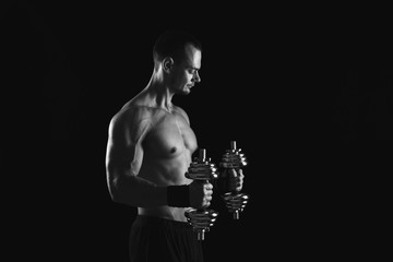 Fototapeta na wymiar Strong athletic man with dumbbell showes naked muscular body