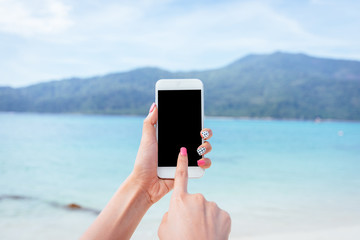 Woman hand holding blank screen smartphone mobile with beautiful sea and island in background