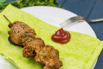 Fried meat on green pita bread with spinach and peas and baked potatoes.