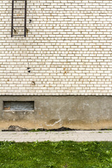 Big fragment of white brick wall with green grass