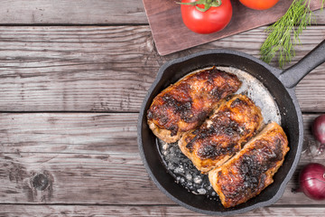 Roasted chicken pieces in cast iron pan top view with copy space