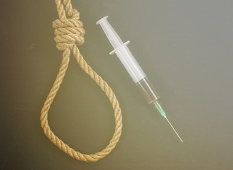 Drugs are suicide. A hinge for the gallows and a syringe with heroin on a black background.