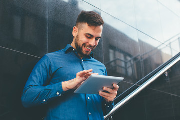 Young handsome man using digital tablet outdoors
