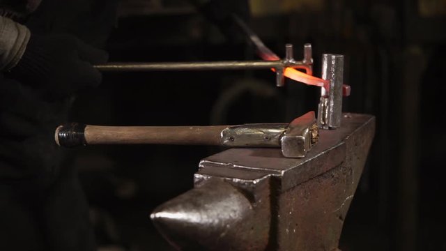 close up shot of the blacksmith's hands, the man is engaged in making horseshoes made of steel for the large-bred animals, the person hammers the material