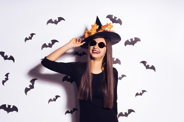 happy woman in a witch costume against the backdrop of bats