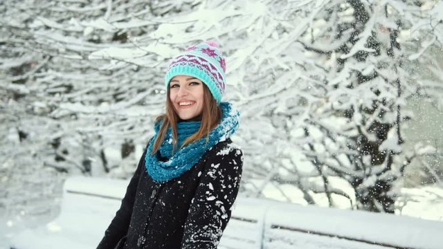 Young happy girl having fun in the winter park, outdoor sunny day slowmotion