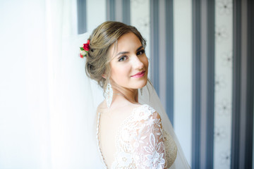 Beautiful bride in white dress posing under curtain